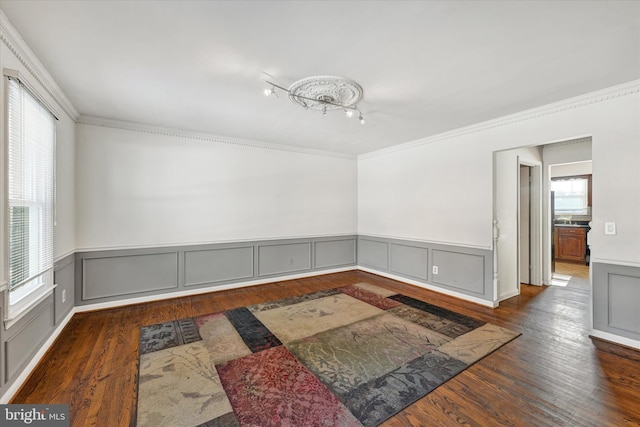 spare room with crown molding, dark wood-type flooring, and a healthy amount of sunlight