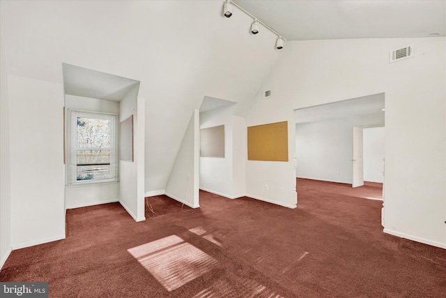 unfurnished living room featuring rail lighting, high vaulted ceiling, and dark carpet