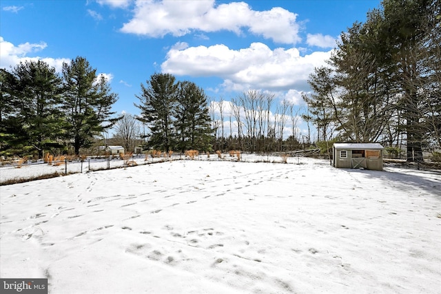 snowy yard featuring a storage shed