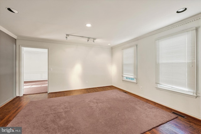 spare room featuring dark hardwood / wood-style flooring, track lighting, and ornamental molding