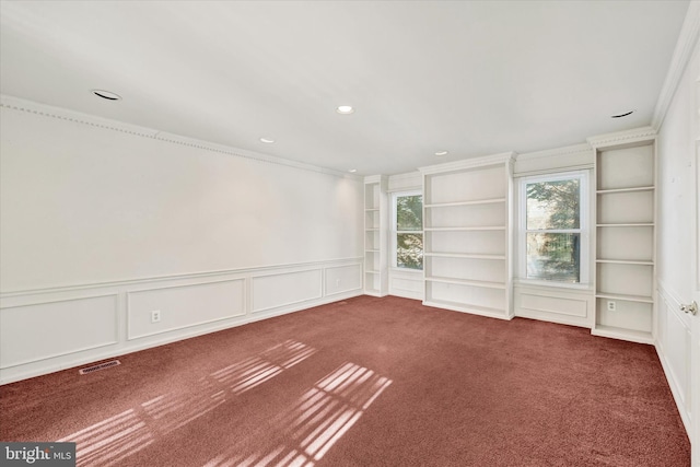 empty room featuring built in shelves, ornamental molding, and dark carpet