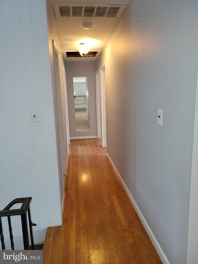 corridor with visible vents, light wood-style flooring, and baseboards