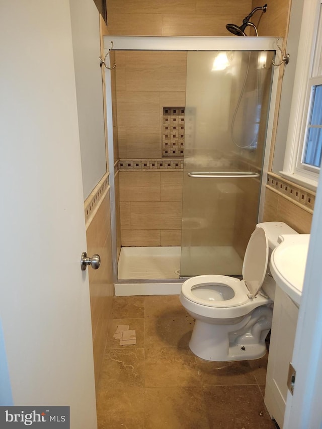 bathroom featuring a shower stall, toilet, and tile walls