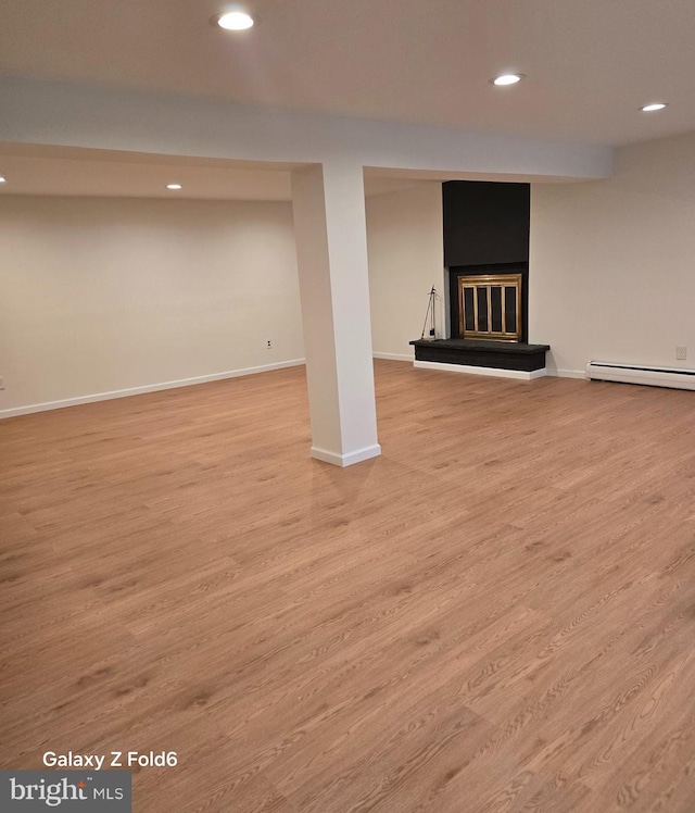 finished below grade area with recessed lighting, baseboards, a glass covered fireplace, and wood finished floors