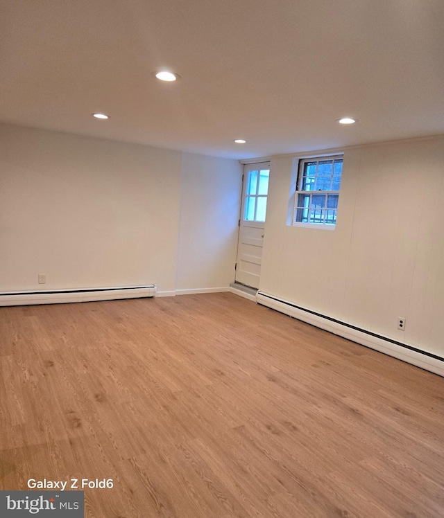 empty room featuring recessed lighting, a baseboard heating unit, baseboards, and wood finished floors