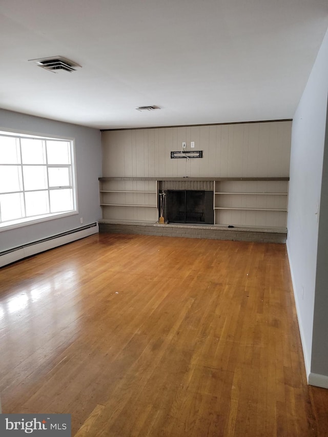 unfurnished living room featuring a fireplace, wood finished floors, and visible vents