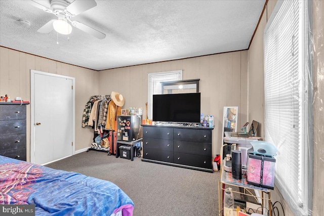 carpeted bedroom featuring a textured ceiling, ceiling fan, and wooden walls