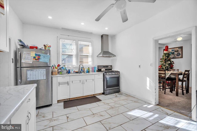 kitchen featuring stainless steel appliances, wall chimney range hood, light colored carpet, white cabinetry, and sink