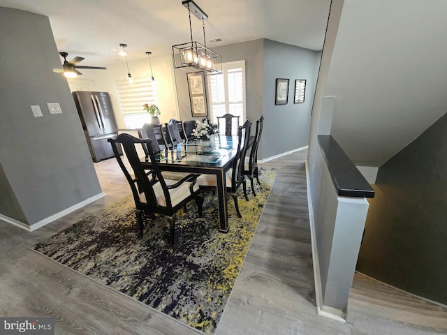 dining area with hardwood / wood-style floors and ceiling fan with notable chandelier