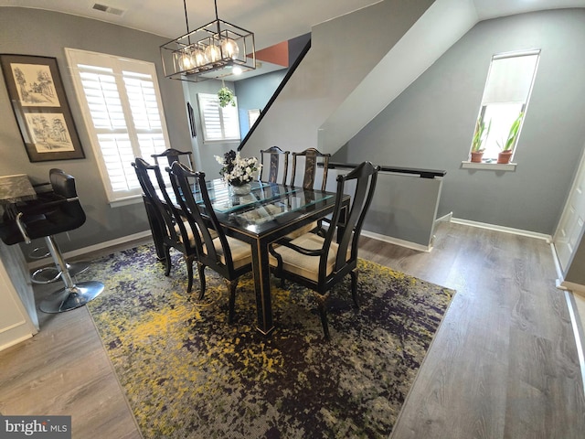 dining space featuring hardwood / wood-style flooring, lofted ceiling, and a chandelier