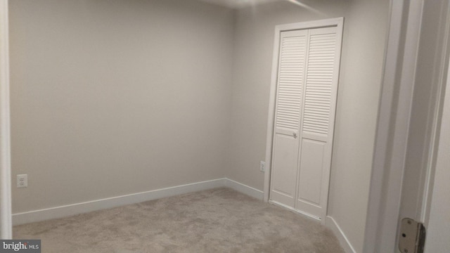 unfurnished bedroom with light carpet and a closet