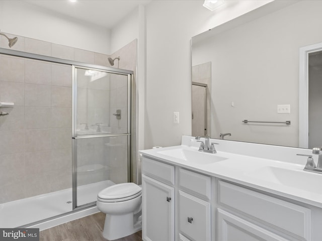 bathroom featuring a shower with door, vanity, hardwood / wood-style floors, and toilet