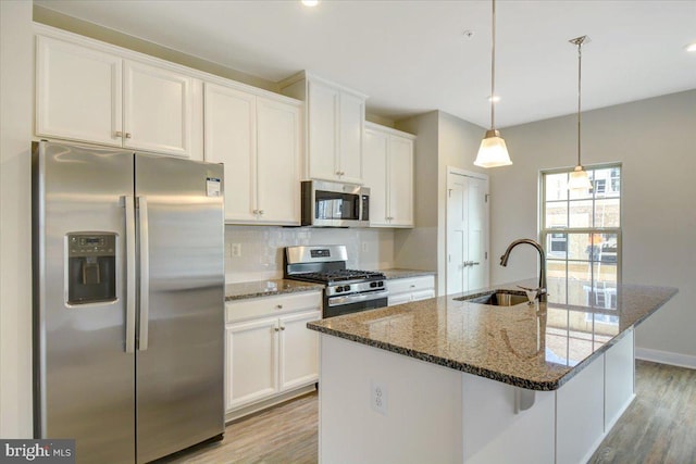 kitchen featuring pendant lighting, sink, appliances with stainless steel finishes, an island with sink, and white cabinets