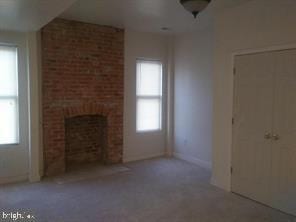 unfurnished living room with carpet and a brick fireplace