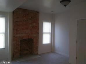 unfurnished living room with a wealth of natural light and a brick fireplace