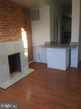 unfurnished living room featuring dark hardwood / wood-style flooring and brick wall