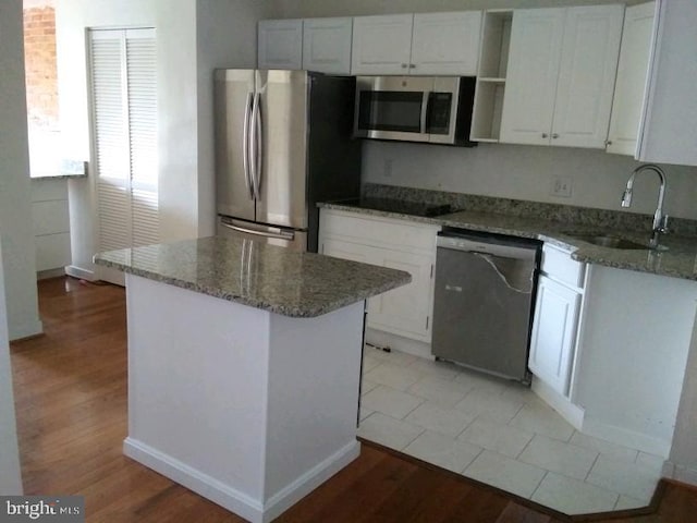 kitchen with stone countertops, stainless steel appliances, white cabinetry, and sink