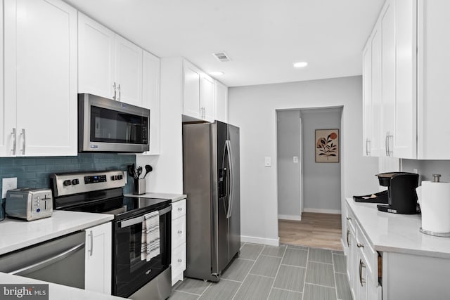 kitchen featuring tasteful backsplash, white cabinets, and appliances with stainless steel finishes