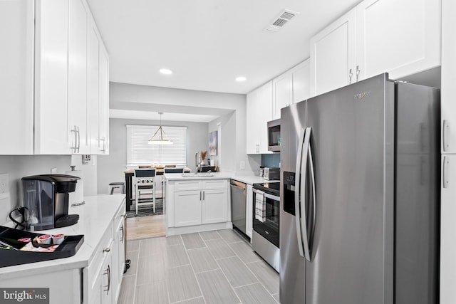 kitchen featuring stainless steel appliances, white cabinetry, hanging light fixtures, and sink