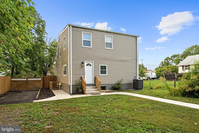 rear view of house featuring a lawn and central air condition unit