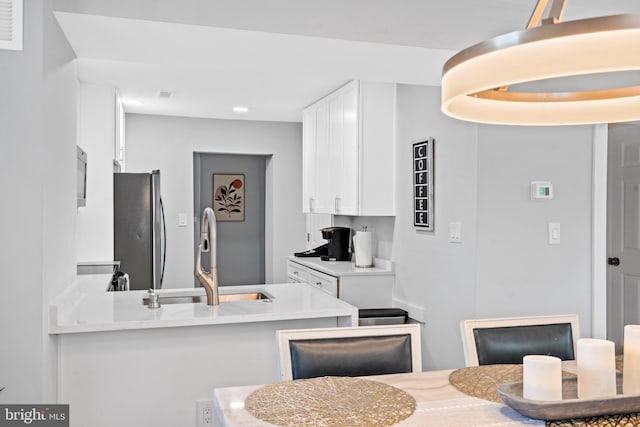 kitchen with white cabinets, stainless steel fridge, kitchen peninsula, and sink