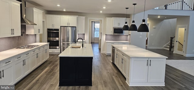 kitchen with appliances with stainless steel finishes, pendant lighting, white cabinetry, an island with sink, and sink