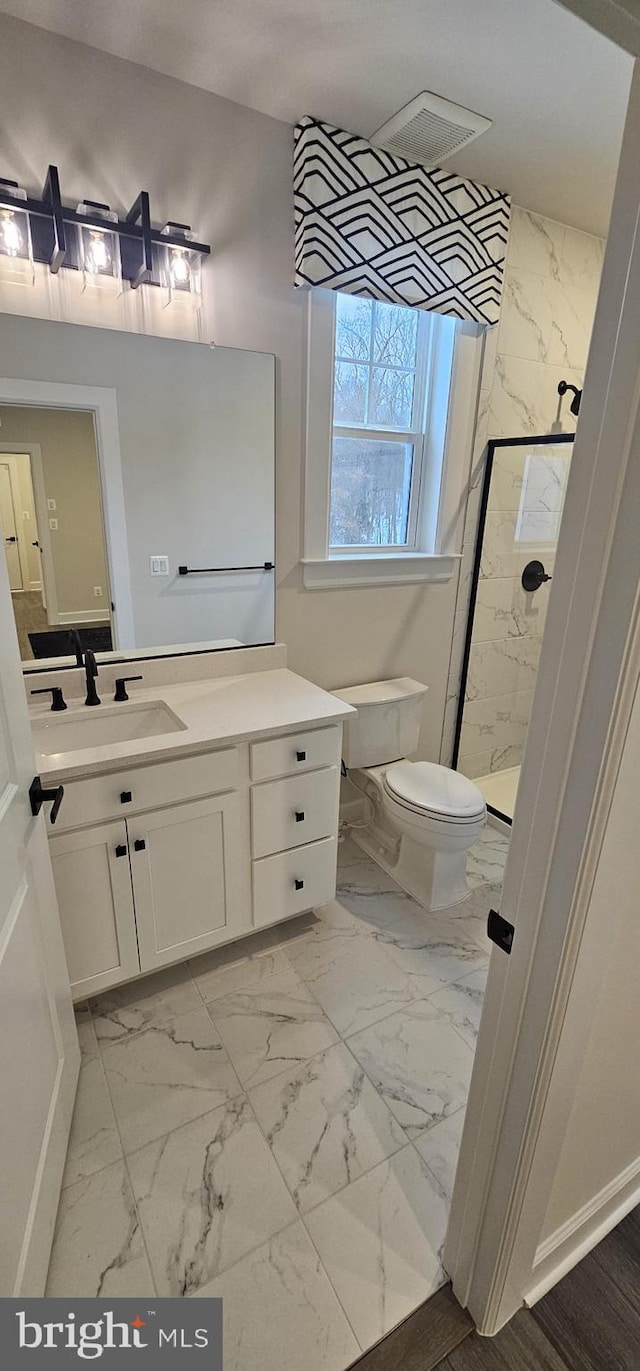 bathroom featuring vanity, toilet, and a shower with shower door