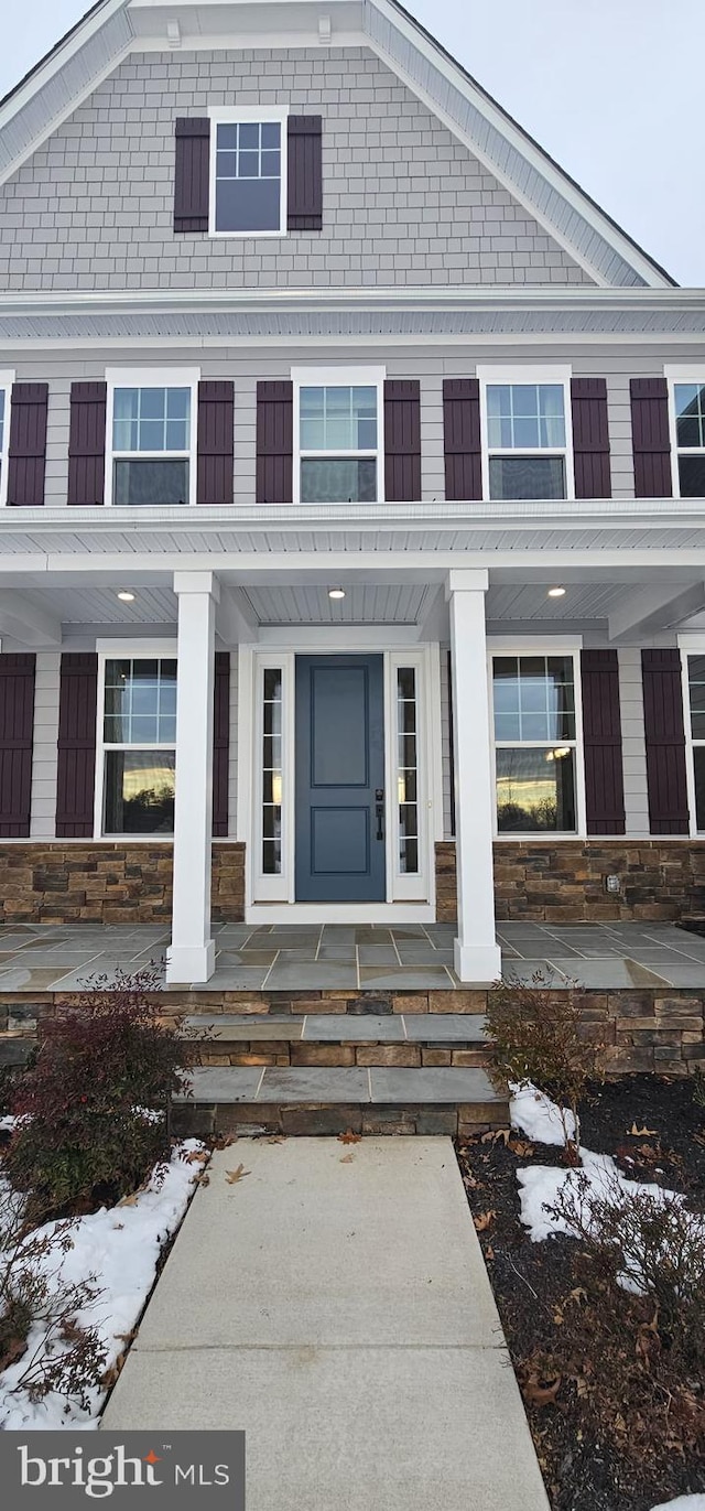 snow covered property entrance featuring a porch