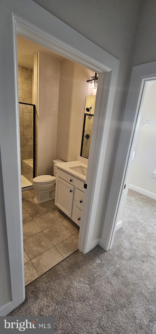 bathroom with tiled shower, vanity, and toilet