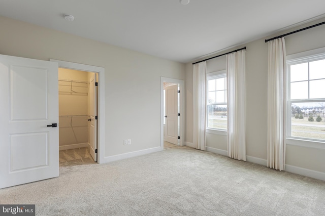 unfurnished bedroom with light carpet and a walk in closet