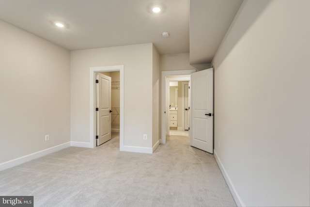 unfurnished bedroom featuring a spacious closet and light colored carpet