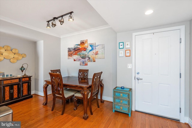 dining space with ornamental molding, hardwood / wood-style floors, and track lighting