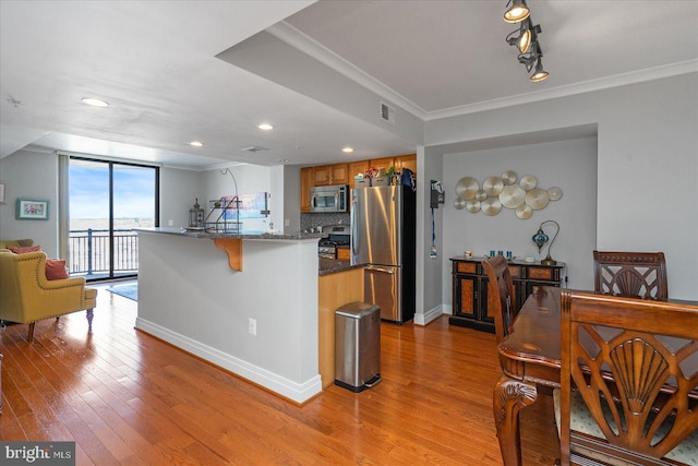 kitchen featuring appliances with stainless steel finishes, a breakfast bar area, backsplash, and light hardwood / wood-style flooring