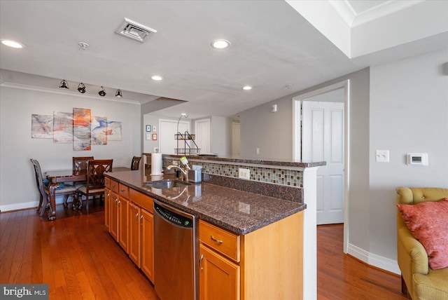 kitchen with sink, dark wood-type flooring, dark stone countertops, an island with sink, and stainless steel dishwasher