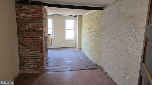 corridor with hardwood / wood-style flooring, beamed ceiling, and brick wall