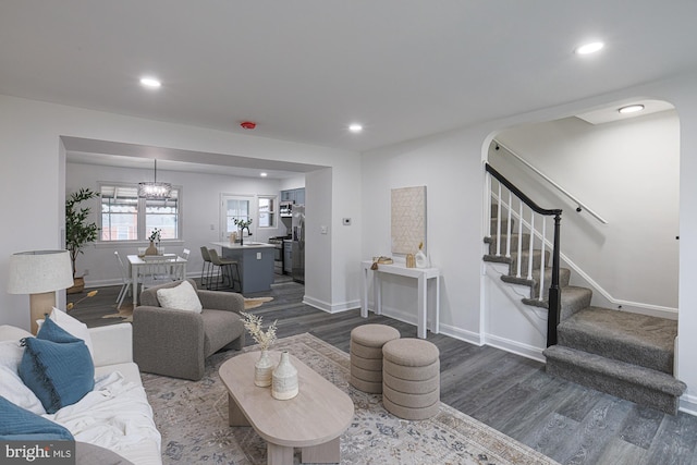 living room with dark wood-style floors, recessed lighting, stairway, arched walkways, and baseboards