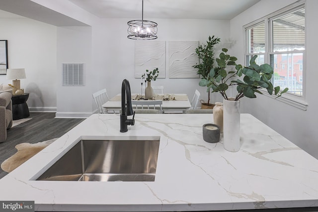 room details with light stone counters, wood finished floors, visible vents, and a sink