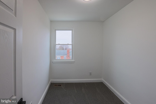 empty room featuring visible vents, baseboards, and dark colored carpet