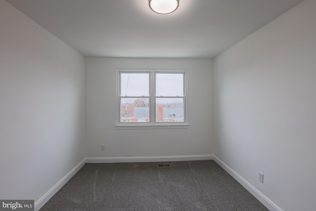 unfurnished room with visible vents, baseboards, and dark colored carpet