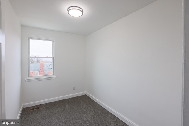 empty room featuring baseboards, visible vents, and dark colored carpet