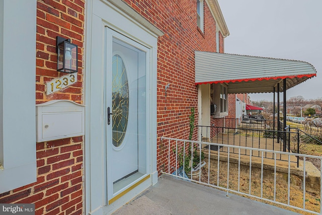 doorway to property featuring brick siding and fence