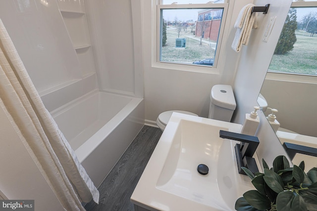 bathroom with toilet, a sink, curtained shower, wood finished floors, and baseboards