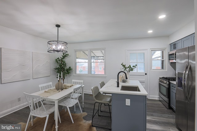 kitchen with a sink, baseboards, light countertops, stainless steel appliances, and dark wood-style flooring