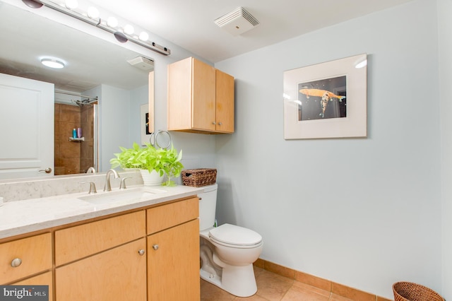 bathroom with toilet, a tile shower, vanity, and tile patterned floors