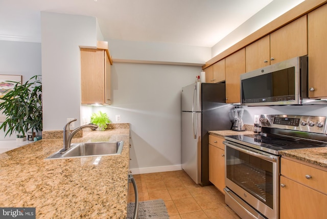 kitchen with sink, light stone countertops, light brown cabinetry, appliances with stainless steel finishes, and light tile patterned flooring