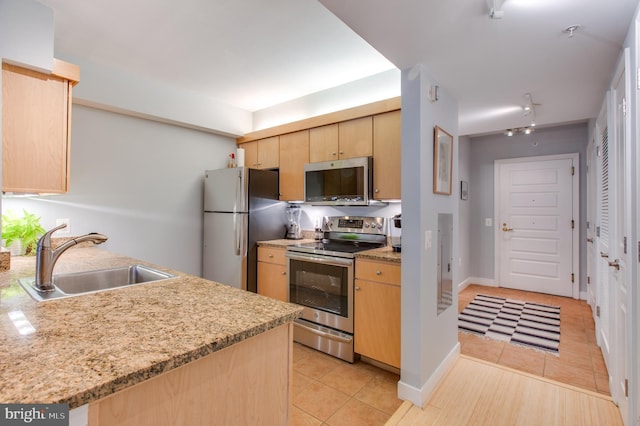 kitchen with sink, light stone counters, light brown cabinetry, light tile patterned floors, and appliances with stainless steel finishes