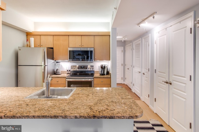 kitchen featuring track lighting, stainless steel appliances, sink, light brown cabinets, and light hardwood / wood-style flooring