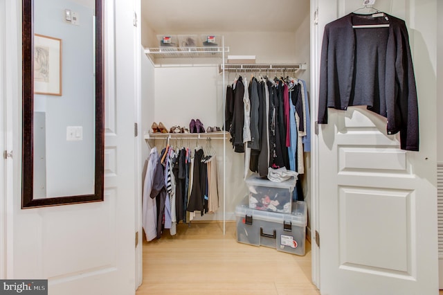 walk in closet with light hardwood / wood-style flooring