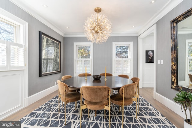 dining room with a notable chandelier, baseboards, light wood-style floors, and ornamental molding