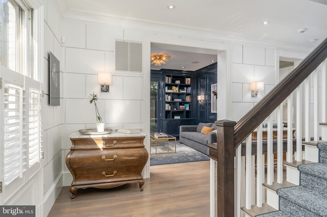 staircase with crown molding, wood finished floors, and visible vents